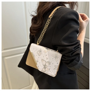 Détail du sac bandoulière carré avec imprimé papillon et chaîne dorée sur le mannequin