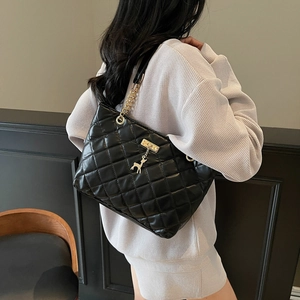 Chic black quilted tote bag with gold chain strap and deer charm on female model