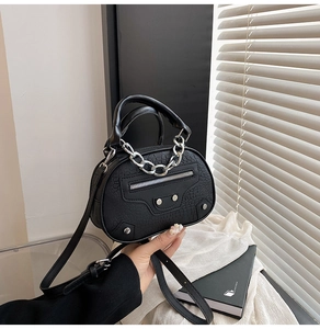 Detail of black faux crocodile shell bag with silver chain and stud accents