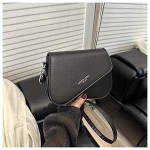 Détail d'un sac bandoulière noir avec texte blanc et boucle en métal argenté