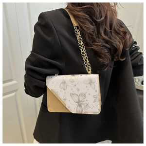 Détail du sac à bandoulière carré beige avec motif papillon et chaîne dorée