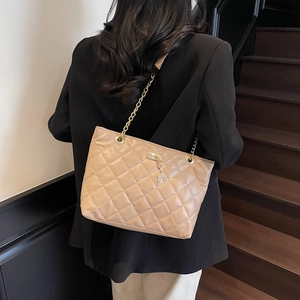 Quilted beige tote bag with gold chain strap and deer pendant shown in a lifestyle view