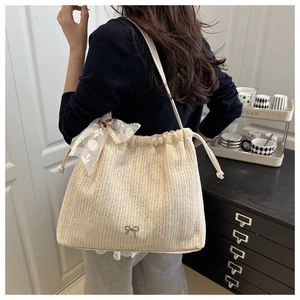 Detail of straw tote bag with lace bow accent and beige woven texture on model