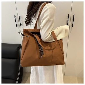 Detail of brown tote bag with woven drawstring decoration and gold hardware rings
