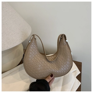 Close-up of khaki woven texture and silver hardware on a crescent hobo shoulder bag