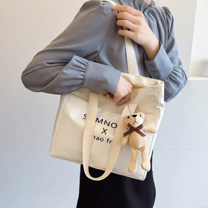 Minimalist white nylon tote bag for women with wide shoulder strap and plush bear charm