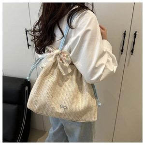 Detail of straw tote bag with floral lace bow and light blue faux leather straps
