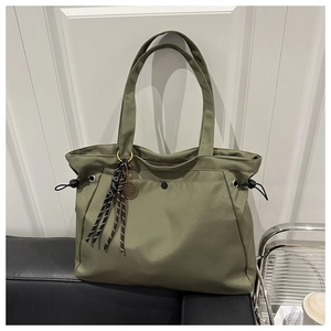 Detail of olive green nylon tote bag with tennis racket charm in a lifestyle interior