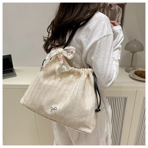 Detail of beige straw tote bag with V-shaped weave, white organza bow and floral embroidery