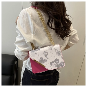 Détail du sac bandoulière rose et blanc avec motif papillon et chaîne dorée sur mannequin