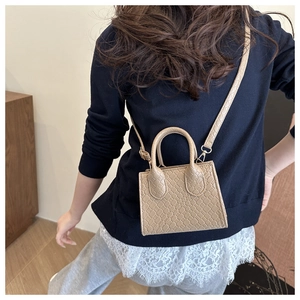 Detail of light beige woven texture crossbody bag with sleek handle and slim strap
