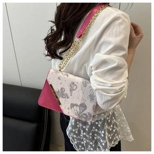 Détail du sac bandoulière rose et blanc avec imprimé papillon et chaîne dorée
