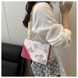 Détail du sac bandoulière rose et blanc avec motif papillon et chaîne dorée