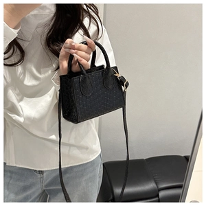 Detail of black faux crocodile leather mini tote bag with gold hardware and strap