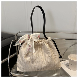 Close-up of beige woven tote bag with lace bow, floral embroidery and metal detail