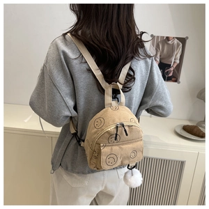 Detailansicht beige Cord-Minirucksack mit schwarzen Smiley-Mustern und Plüsch-Anhänger