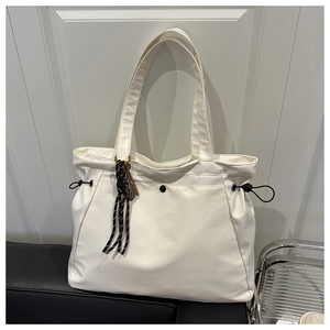 Detail of white large capacity tote bag with black drawstring and striped ribbon accent