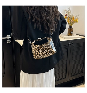 Detail view of a leopard print crossbody bag with metallic clasp and adjustable strap