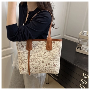 Detail of woven tote bag featuring cute cartoon patterns and brown leather straps