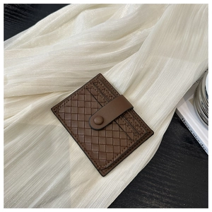Vue macro d'un porte-cartes en cuir tressé marron foncé avec fermeture à bouton-pression