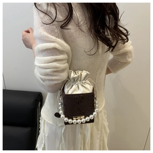Detail of snake skin texture bucket bag with pearl handle and drawstring closure