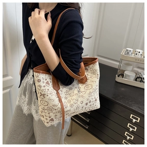 Detailed close-up of woven tote bag featuring brown heart motifs and leather shoulder straps