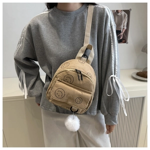 Detail eines beigen Cord-Rucksacks mit Smiley-Print und weißem Plüsch-Anhänger für Damen