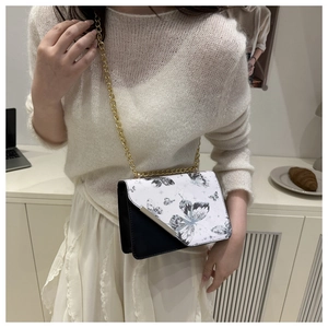 Détail d'un petit sac carré à imprimé papillon et bandoulière en chaîne dorée