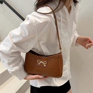 Brown crocodile embossed crescent shoulder bag featuring a gold bow accent for women