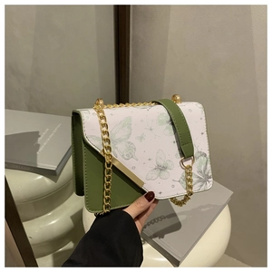 Détail du sac à bandoulière bicolore vert et blanc avec motif papillon et chaîne dorée