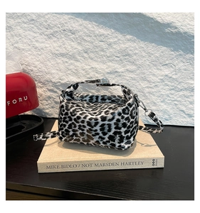 Detail of glossy leopard print handbag with silver buckles and a detachable strap