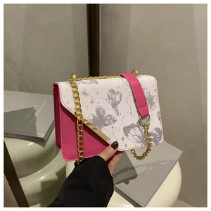 Détail du sac bandoulière en cuir rose et toile fleurie avec chaîne dorée et imprimé papillon