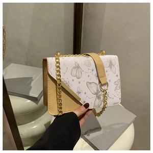 Détail d'un sac à bandoulière carré avec imprimé papillon gris et chaîne dorée