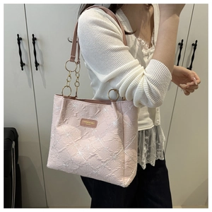Detail of pink tote bag with floral embroidery and golden chain shoulder strap