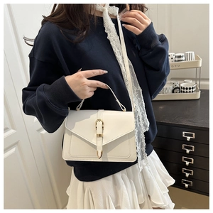 Détail d'un sac à main minimaliste en cuir blanc cassé avec boucle dorée et anse en métal
