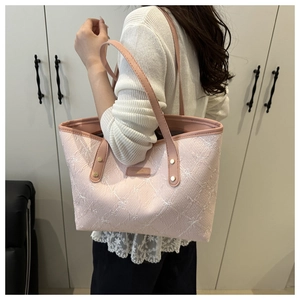 Detail of pink embroidered tote bag with floral patterns and leather straps on model