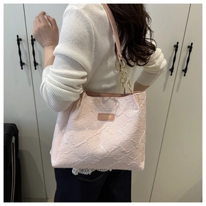 Detail of pink floral jacquard tote bag featuring gold chain strap and brand logo