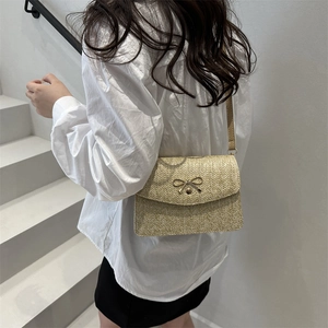 Beige woven crossbody bag with metallic bow detail shown on a model in daily life