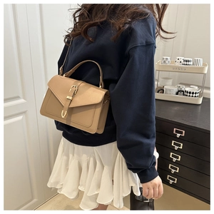 Détail du sac carré en cuir kaki avec boucle dorée vintage et bandoulière de côté