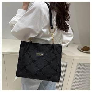 Detail of black tweed tote bag with sequins, gold chain hardware, and leather strap