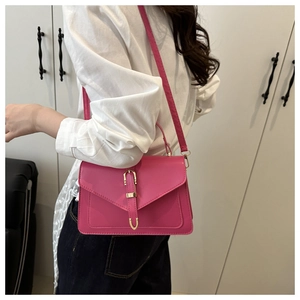 Détail du sac bandoulière rose fuchsia avec boucle métallique dorée en U sur le rabat