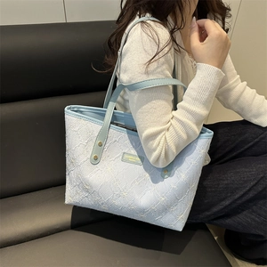 Light blue floral embossed tote bag with leather straps worn by model for daily commute