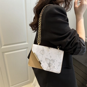 Sac bandoulière blanc imprimé papillon avec chaîne dorée porté par un mannequin
