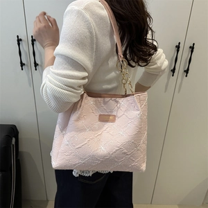 Sac cabas rose avec motif géométrique en relief et bandoulière chaîne dorée porté