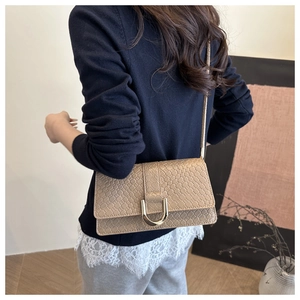 Detail of khaki square crossbody bag with snake texture and golden horseshoe buckle