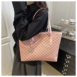 Detail of pink tote bag featuring all-over M pattern and round metallic M logo charm