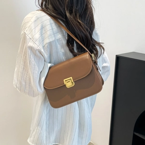 Retro brown leather crossbody bag with a gold square buckle shown on a model side view