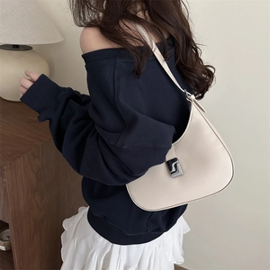 Minimalist creamy white crescent shoulder bag with silver hardware on a female model