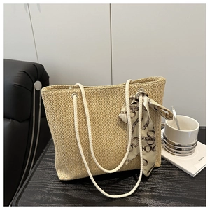 Detail of straw tote bag with V-weave pattern, rope handles, and decorative silk scarf