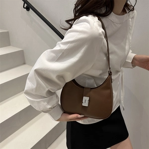 Brown half-moon underarm bag with unique silver buckle shown on minimalist model